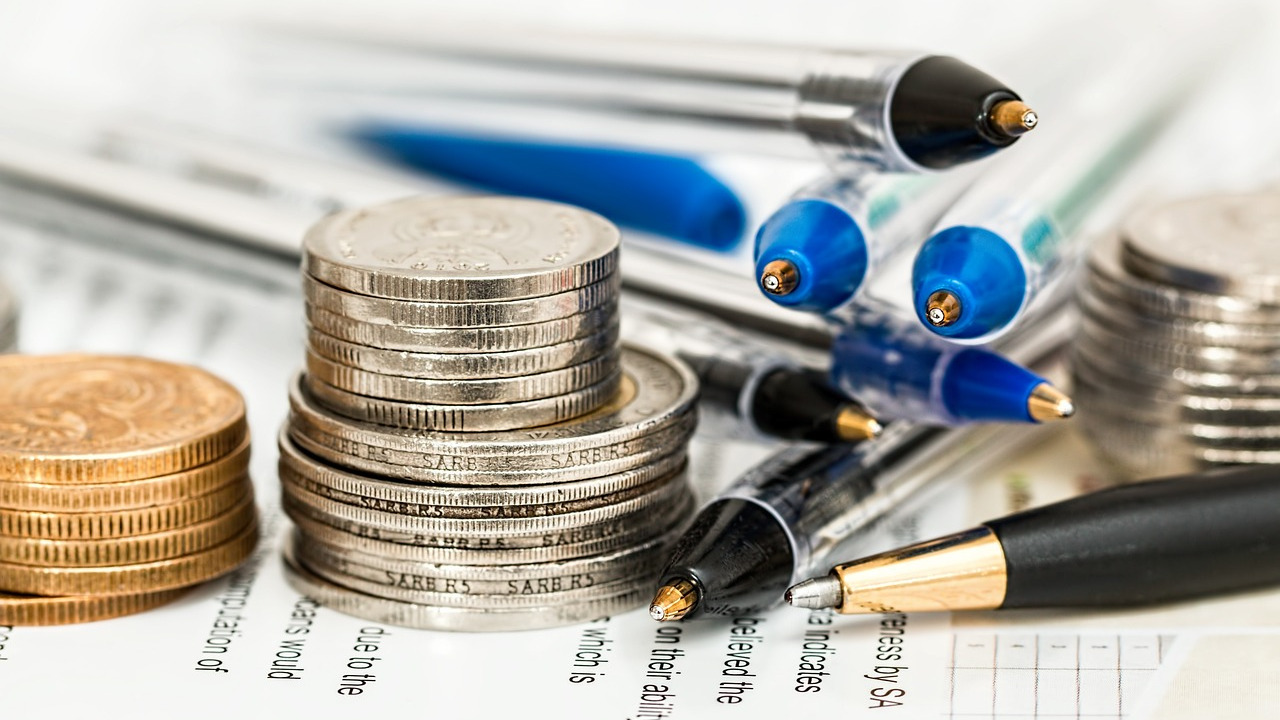 Stacks of gold and silver coins placed on financial documents with pens, symbolizing international tax policy, compliance, and OECD’s Pillar One Amount B framework.