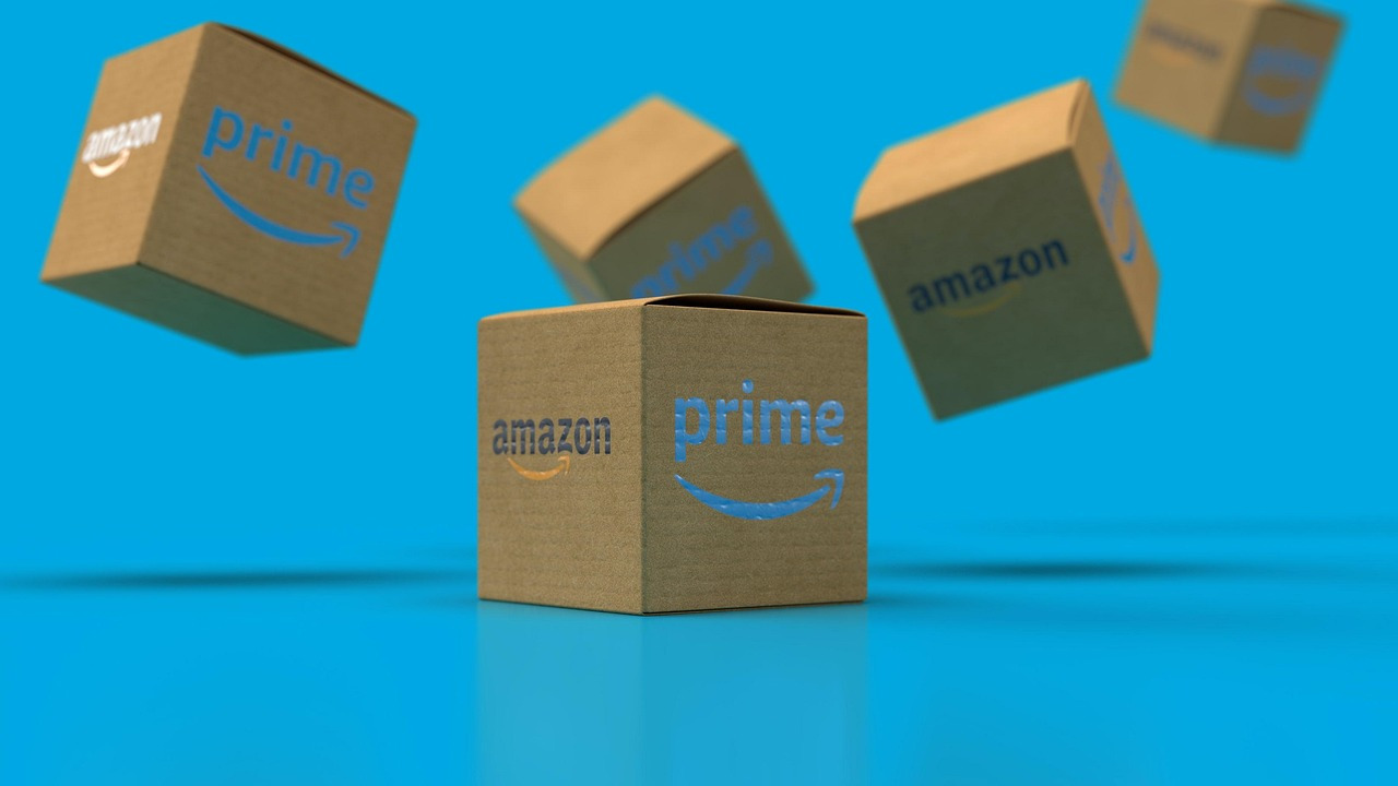 Multiple Amazon Prime branded cardboard boxes floating on a blue background, representing Amazon's e-commerce operations, linked to a €1.2 billion VAT fraud probe in Italy.