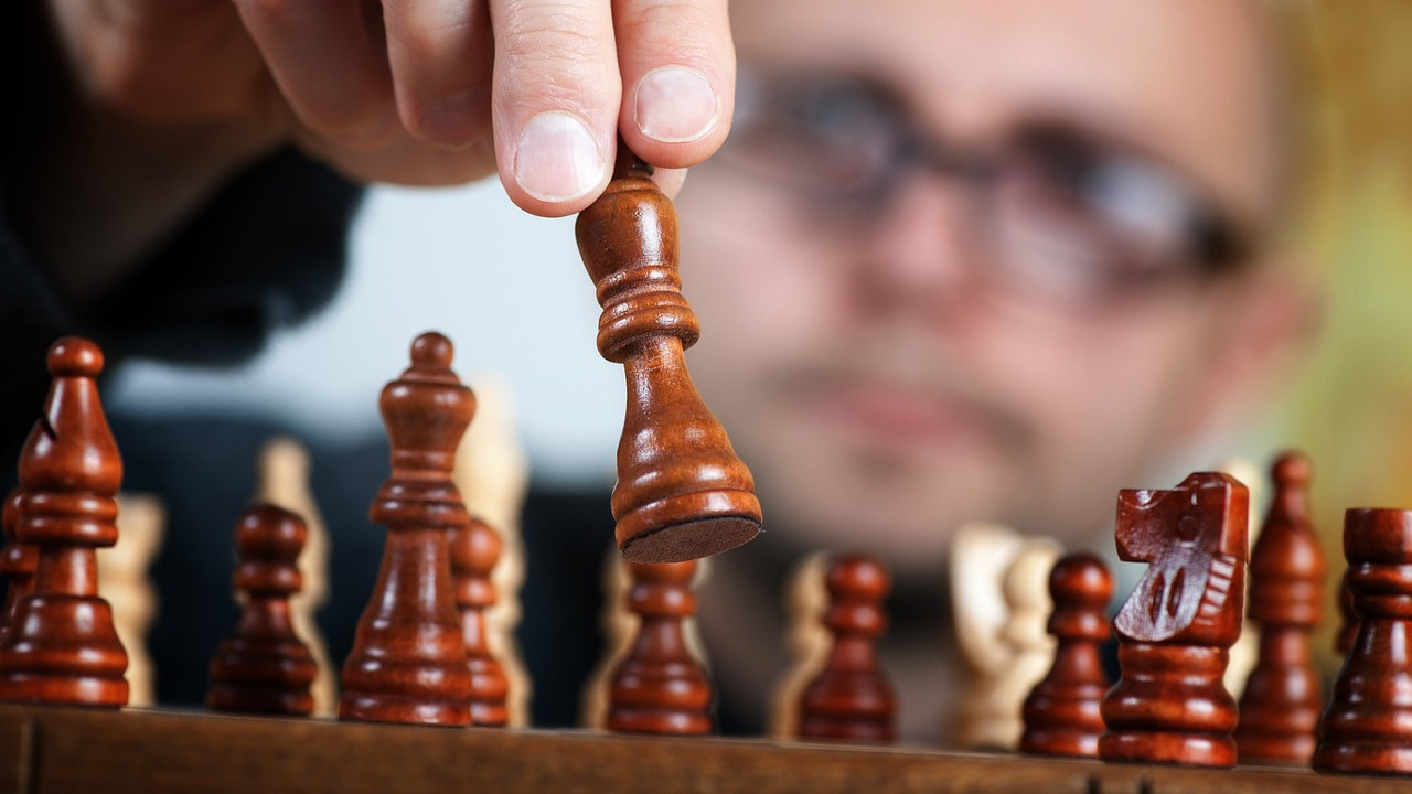 A person making a strategic chess move, symbolizing corporate decision-making and business restructuring.